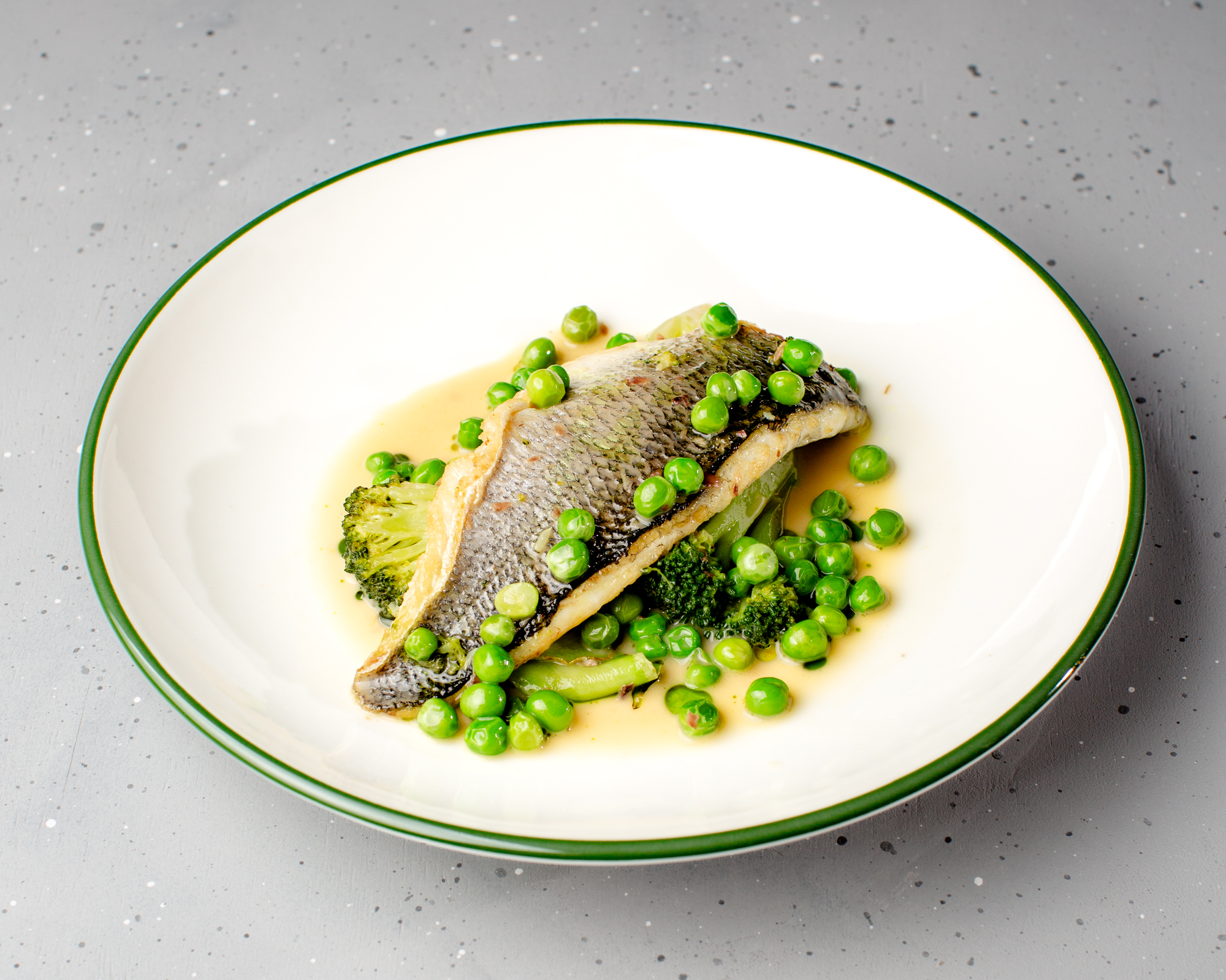 Sea bass with zucchini, green peas, and lemon oil